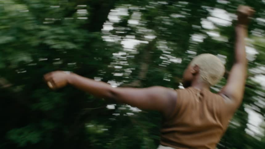 A woman dances under trees