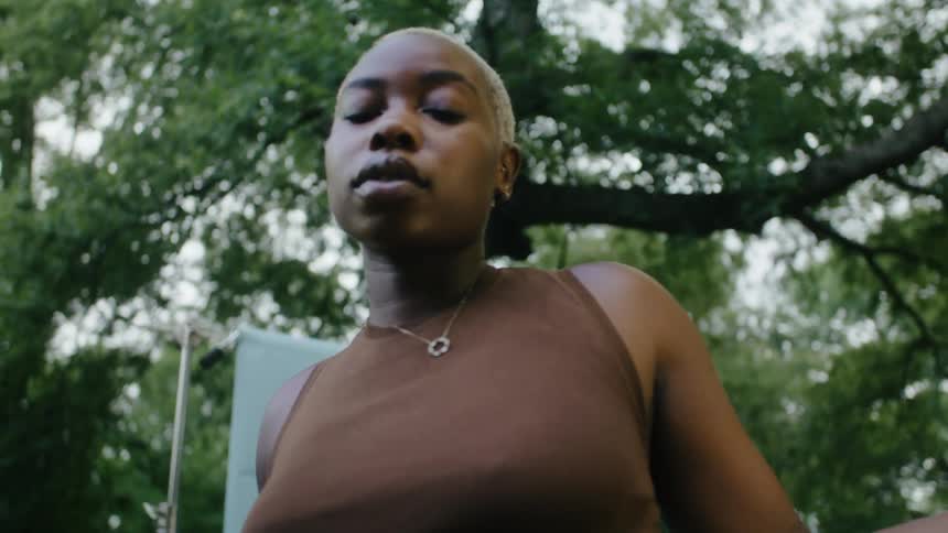 A woman is standing outside and moving her hands and arms in a dancing motion