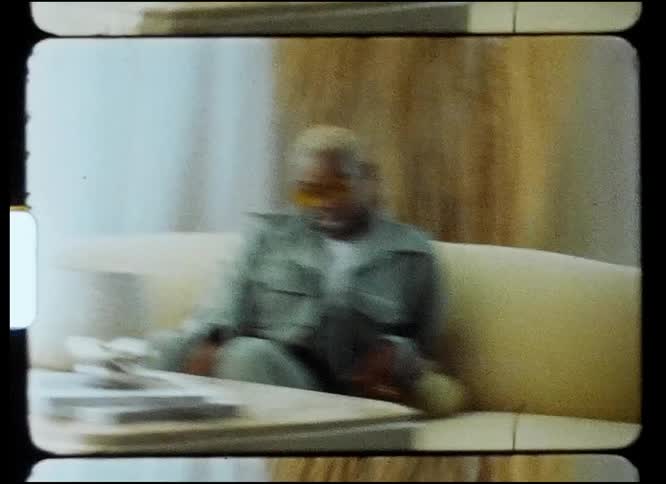 Footage of a woman sitting on a couch is displayed