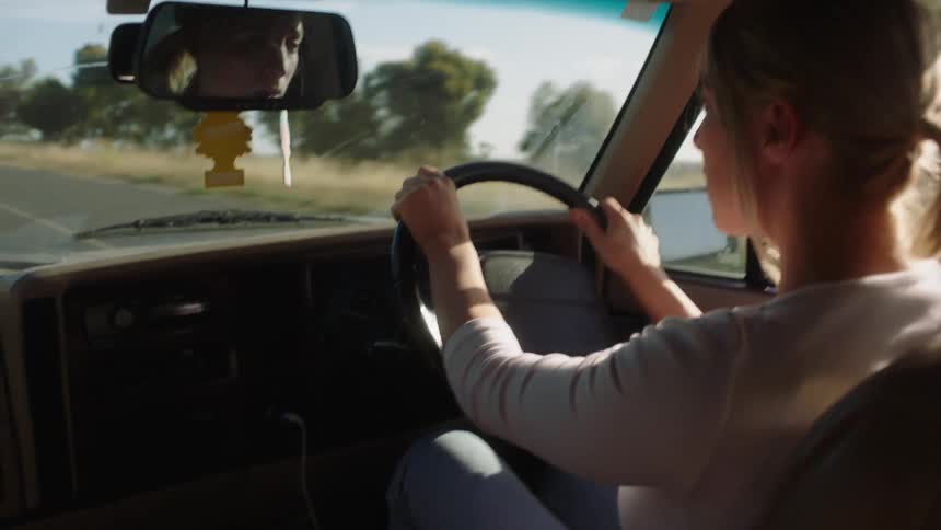 A woman is driving a vehicle on a road during spring
