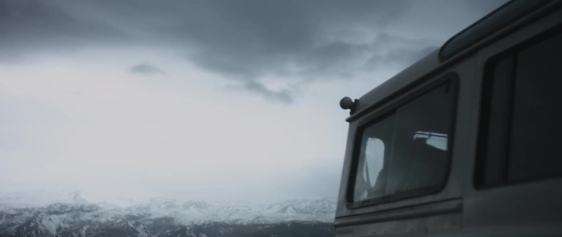Side view of white jeep against the distant snowy mountains under the clouds