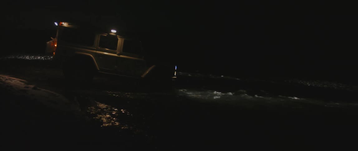 A person drives a jeep into a river