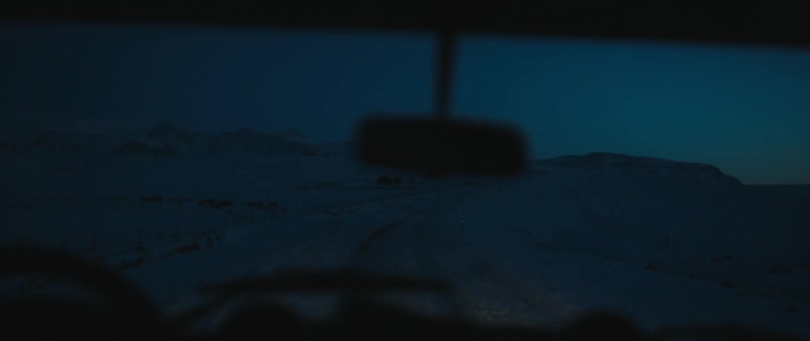 Jeep drives on snowy dirt road at night