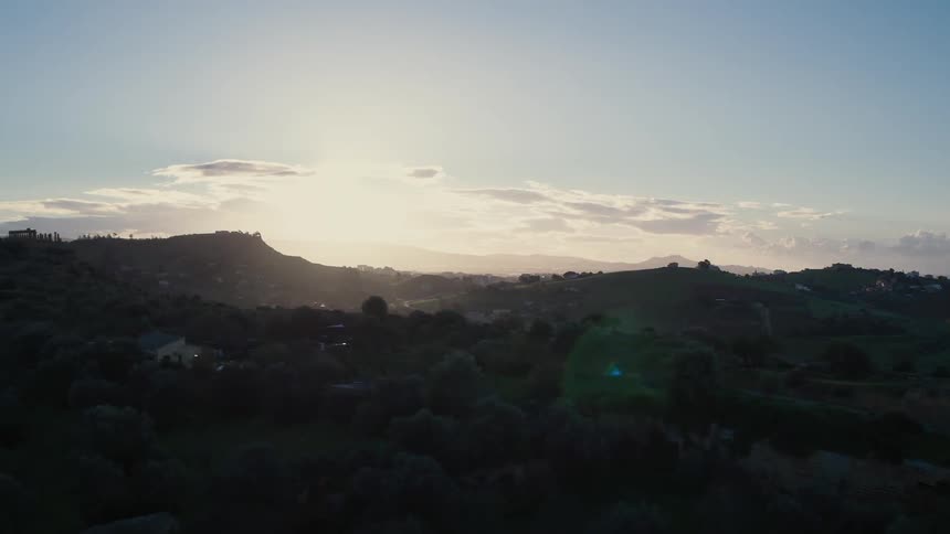 The sun shines from behind a mountain