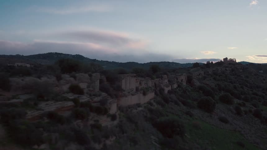 A bush covered hill at sunset