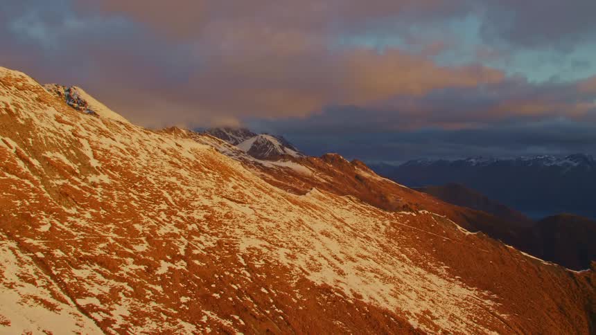Snow dusted mountain peaks and ridges under a cloudy sky