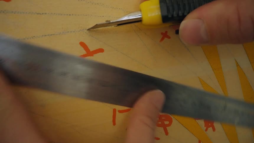 A man uses a ruler and box cutter to mark lines on a board