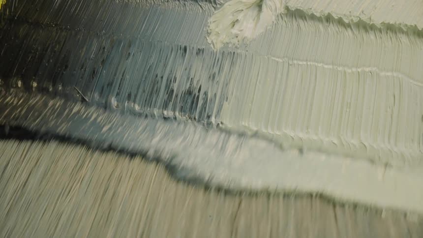 A paint brush is used to create textured lines on a flat surface
