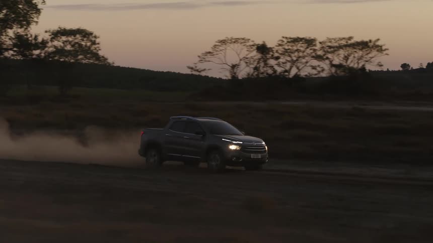 Short bedded truck kicks up dust as it drives past hills under a red tinted sky