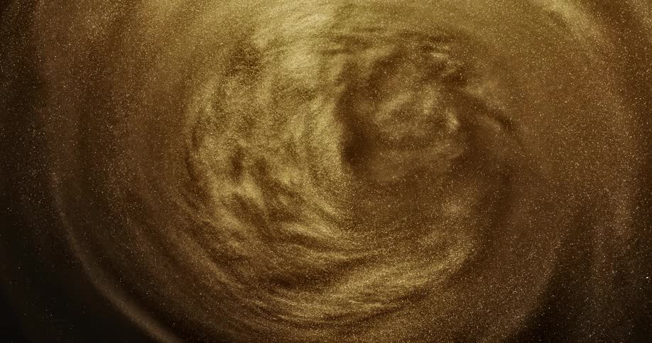 Gold sand flows and swirls making forming shapes as it spins