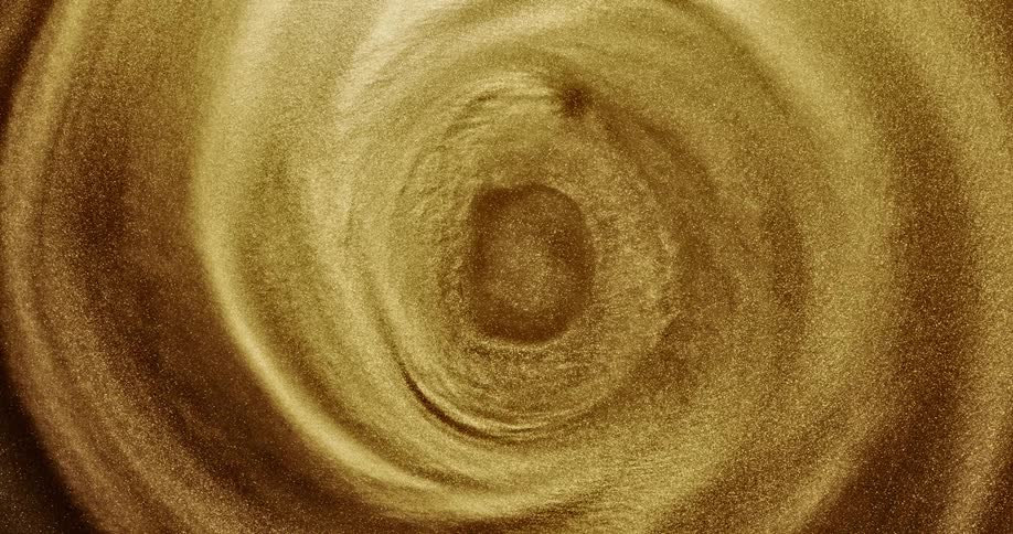 A golden organic liquid substance sparkles as it swirls and ripples