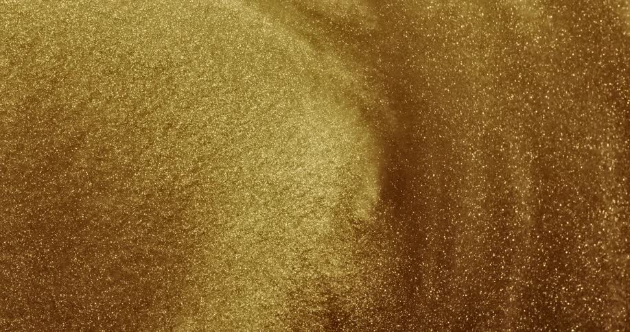 Gold glittery liquid is shown highly magnified swirling around fast and then slow