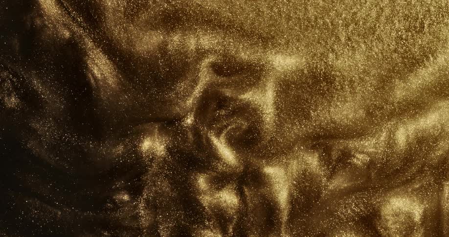 Gold particles flow and spin forming small hills before moving quickly and creating a cloud
