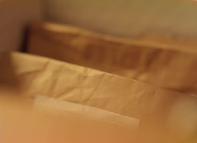 A person picks up a flier from a box of pre packaged takeout food
