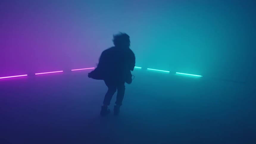 A man is spinning around on a lit stage as he plays guitar