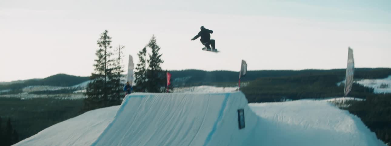 A man rides his snowboard on a course and jumps off a ski jump
