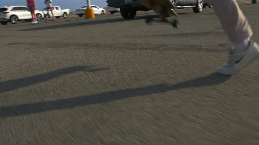A person is riding a skateboard through the parking lot