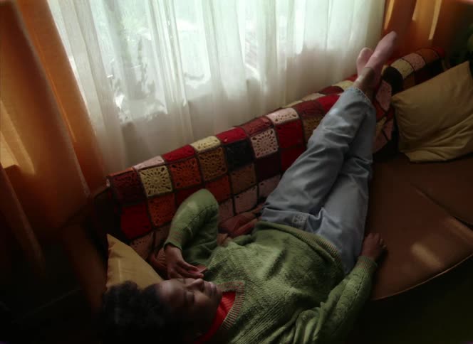A woman talks on the phone while lying on the couch