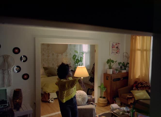 A woman sitting at home stands up and drinks out of a wine bottle and then starts to dance