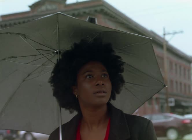 A woman is walking through a city while its raining