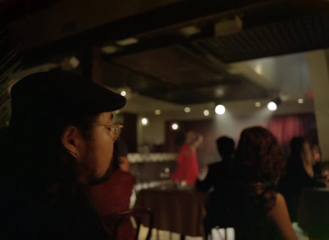 A man smokes a cigarette while sitting inside a restaurant