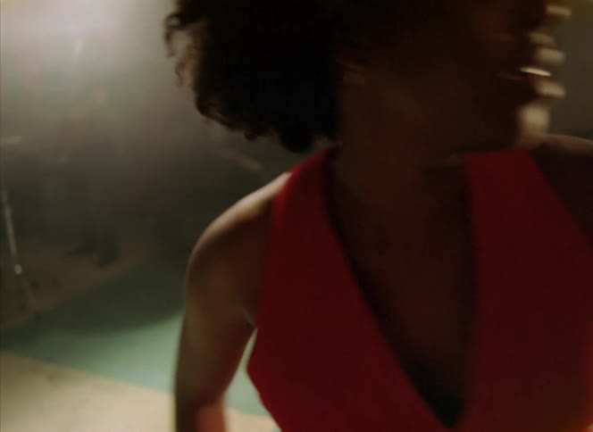 Barefoot woman wearing a red dress dances in front of a band on a restaurant
