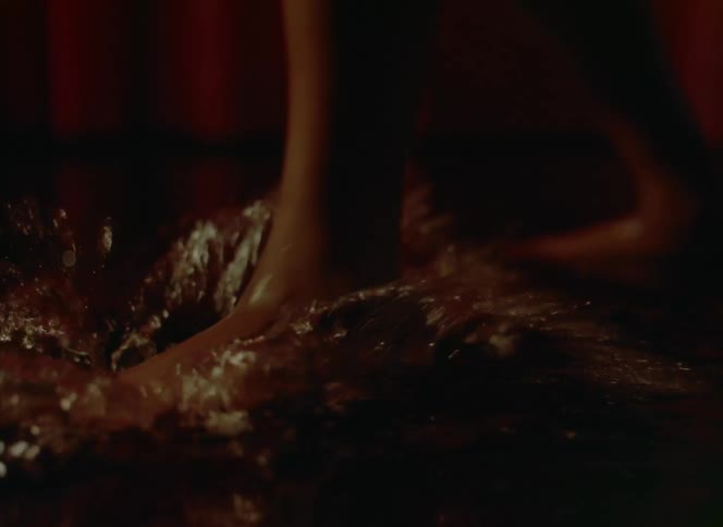 A woman repeatedly stomps her bare foot into a puddle of water splashing it up