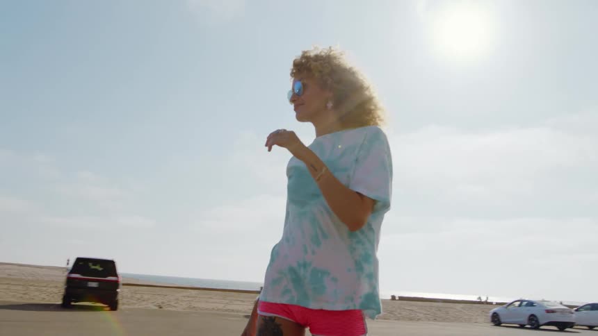 There is a woman that is skateboarding on the street in the middle of the day