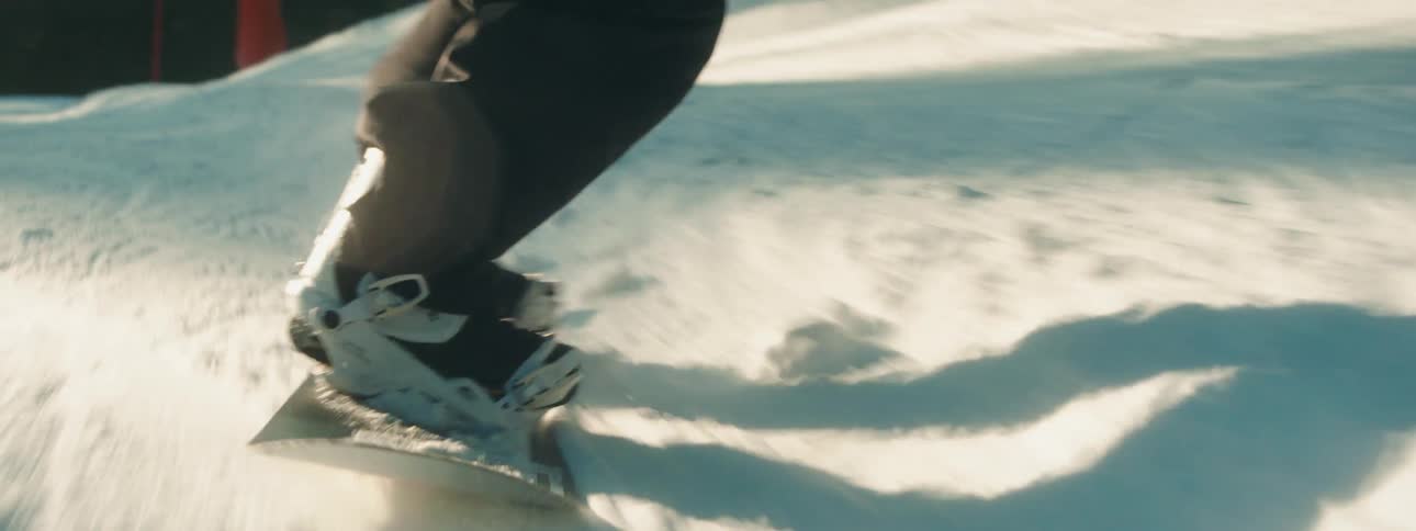 Snowboarder rides over snow covered slope near conifer forest