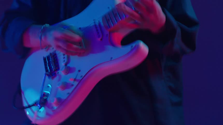 A man playing the guitar during a music performance with flashing colorful lights