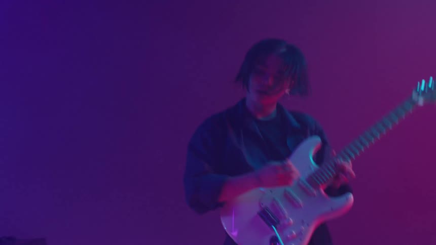 A band plays performs together in room of flashing lights and mist