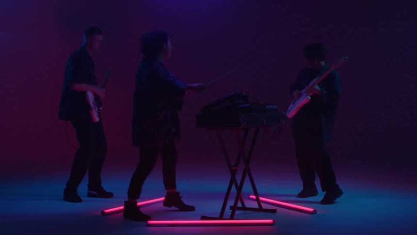 Band of happy excited musicians playing on stage under colorful changing lights