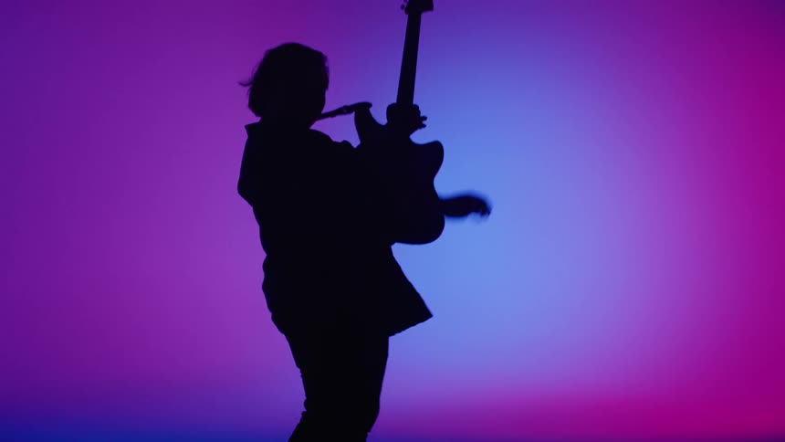 A person is playing a guitar in front of a blue backdrop