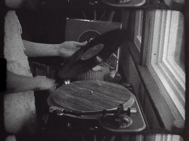 A man wipes off a vinyl record before placing it on a record player