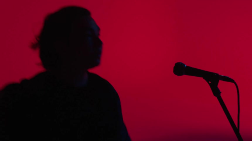 A man dances and reaches for his microphone