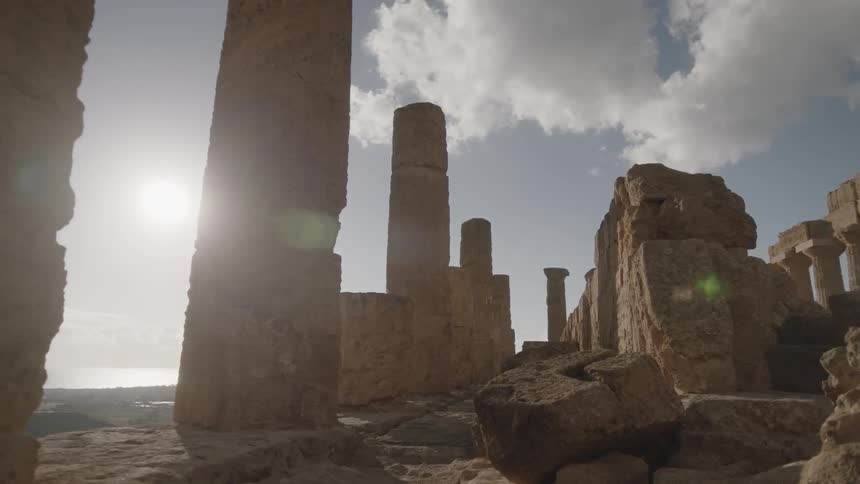 The sun shines down on stone pillars and ruins