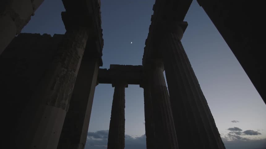 The moon through weathered stone pillars