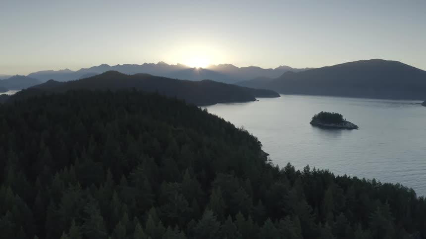 The sun is rising over a mountain range with a large lake
