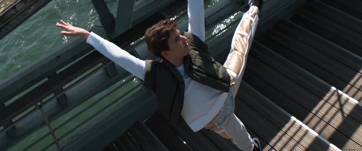 A young man leaps straight up into the air while on a bridge bringing his legs together in air