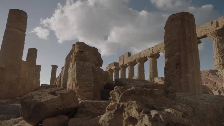 Clouds float over stone pillars and ruins