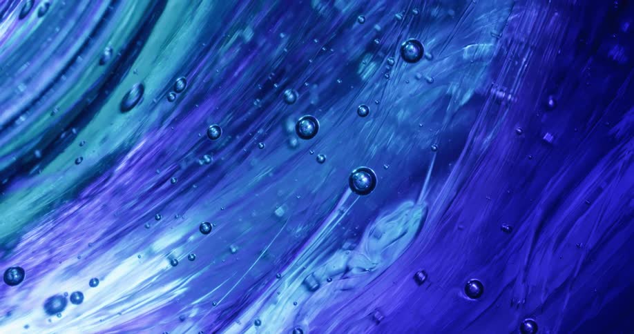 Close up of waves of thick translucent gel tinted with blue ink swelling and bubbling up