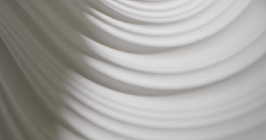 Light shines on a white swirling substance and creates shadows in the grooves