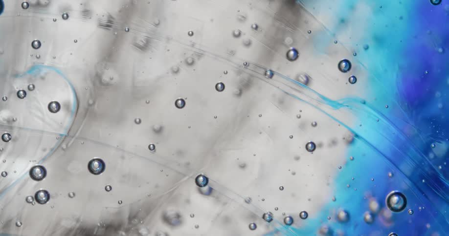 Air bubbles form on the surface of a clear viscous liquid
