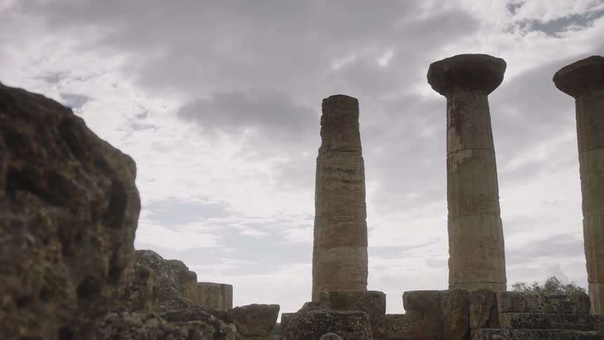 Ancient columns stand against a cloudy sky