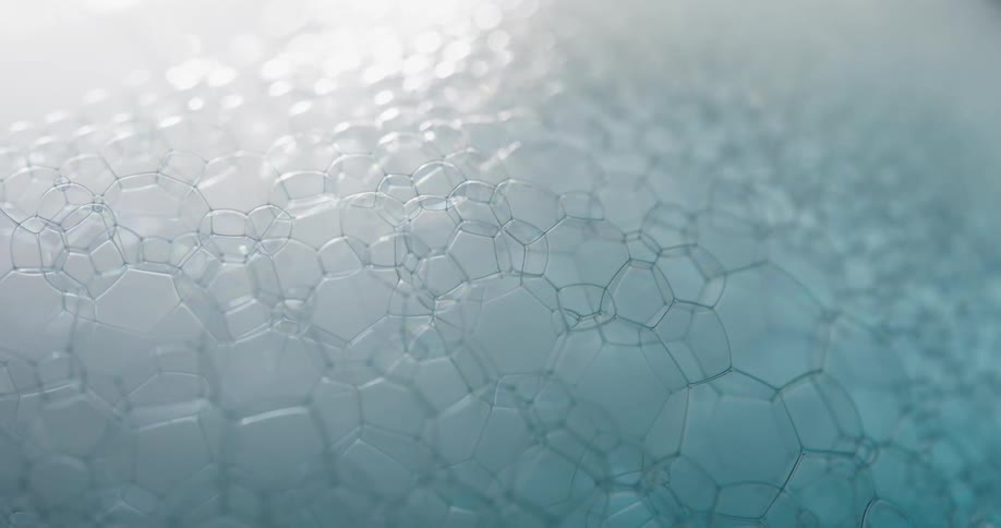 Close up of a tight group of small blue soap bubbles moving while popping