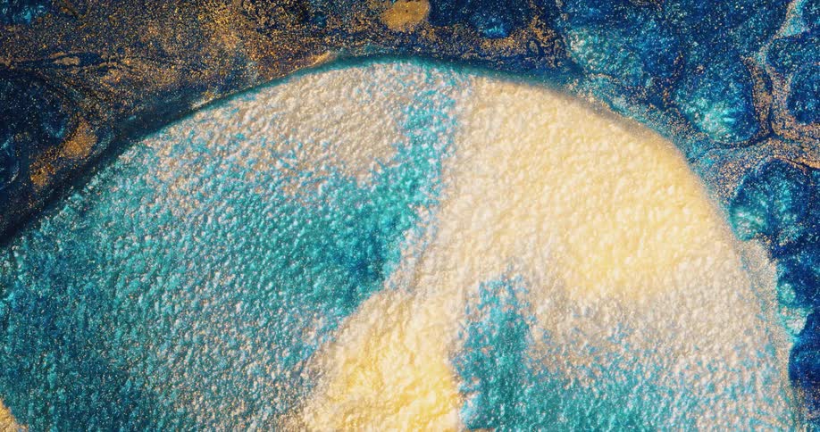 Gold shimmer expands in blue liquid
