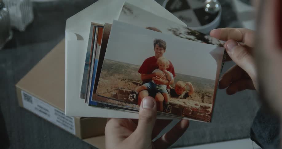 Man looks through family photographs of father and son and son grows