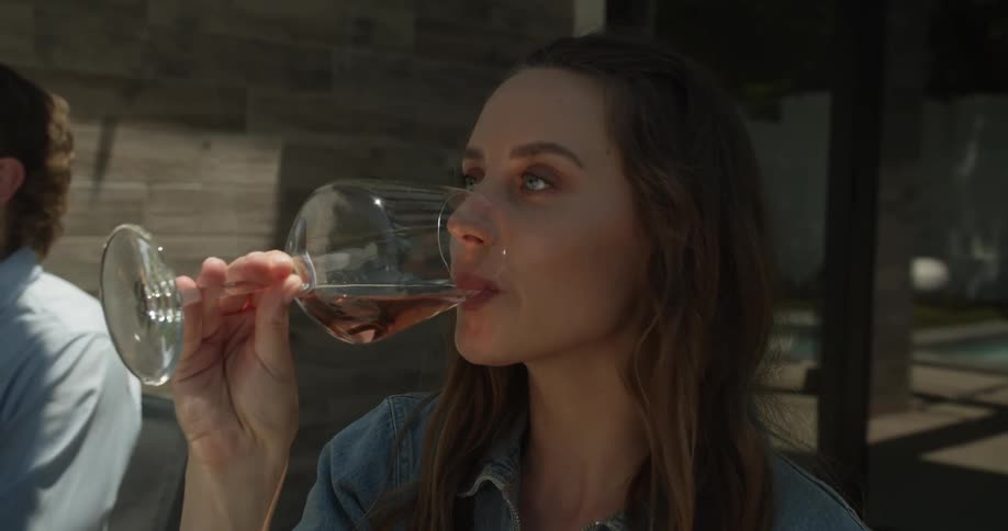 A group of people sit outside at a table at a restaurant and raise their wine glasses as they toast