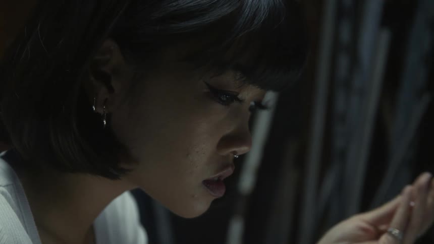 Woman with bob hairstyle earrings piercing and white top uses laptop in room