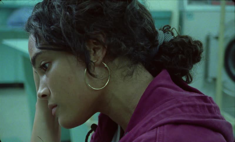 A woman sitting in a laundromat looking weary and frustrated